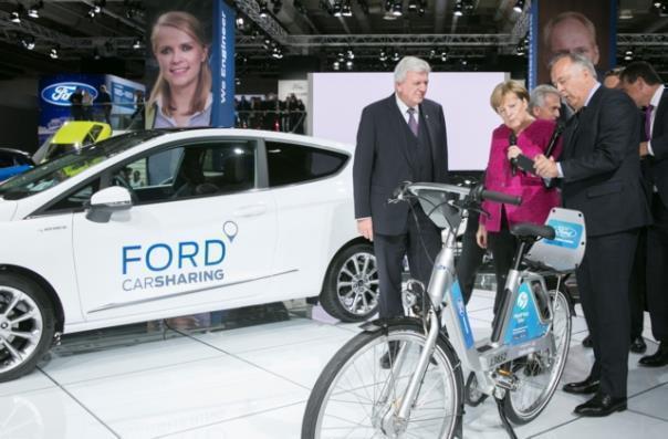 IAA-Rundgang der Kanzlerin (v.r.): Gunnar Herrmann, Vorsitzender der Geschäftsführung der Kölner Ford-Werke, erläutert Angela Merkel und Hessens Ministerpräsident Volker Bouffier das Car- und Bikesharingangebot.  Foto: Auto-Medienportal.Net/Ford